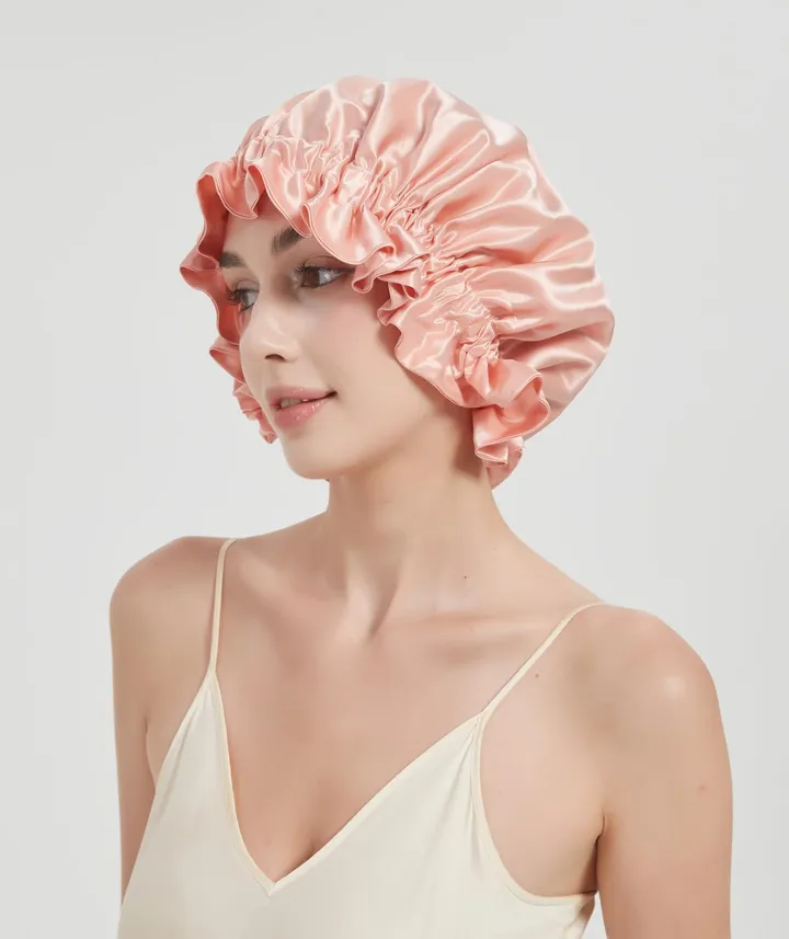 A woman wearing a pink silk sleep bonnet